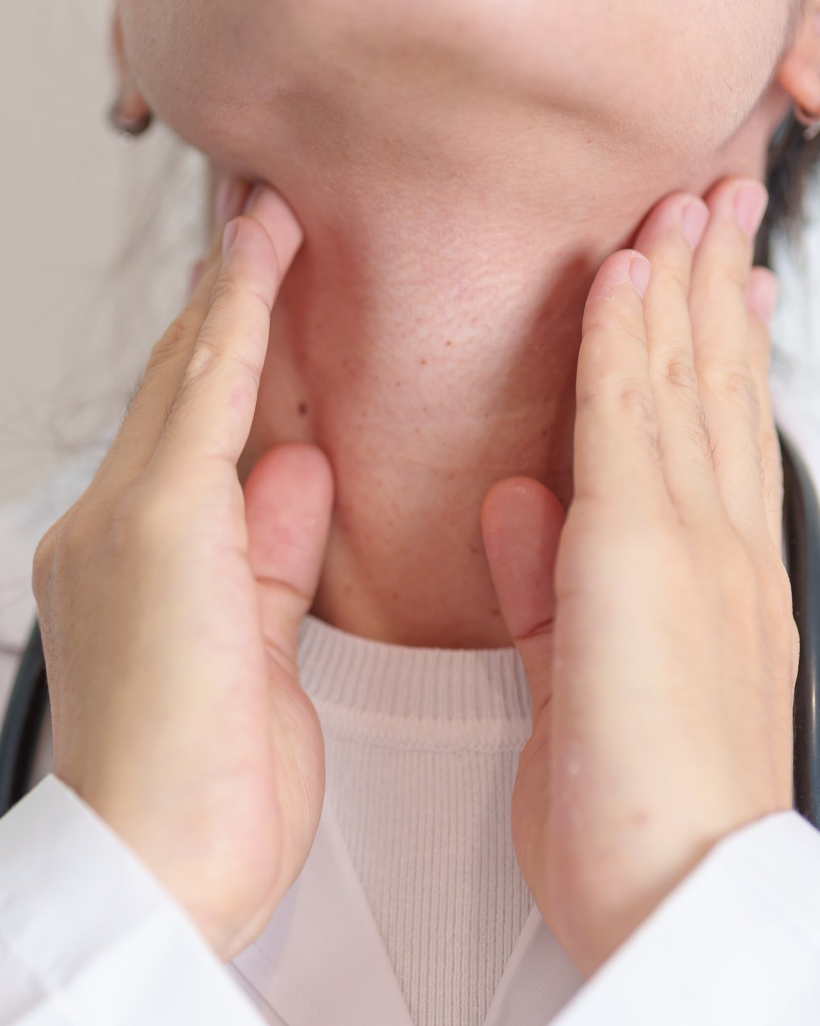 Clinician examining a patient's thyroid