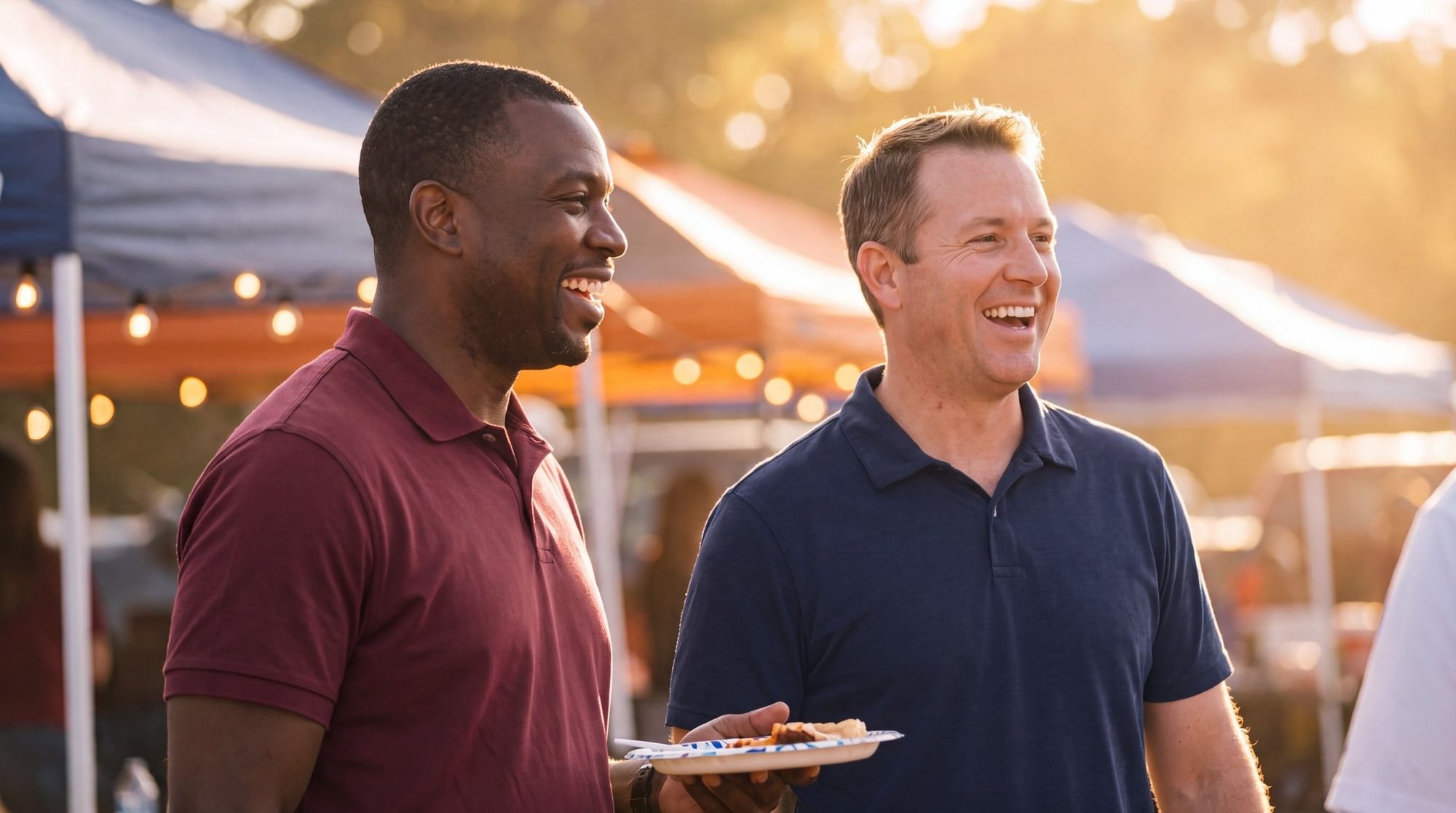 Two men laughing together at a football tailgate